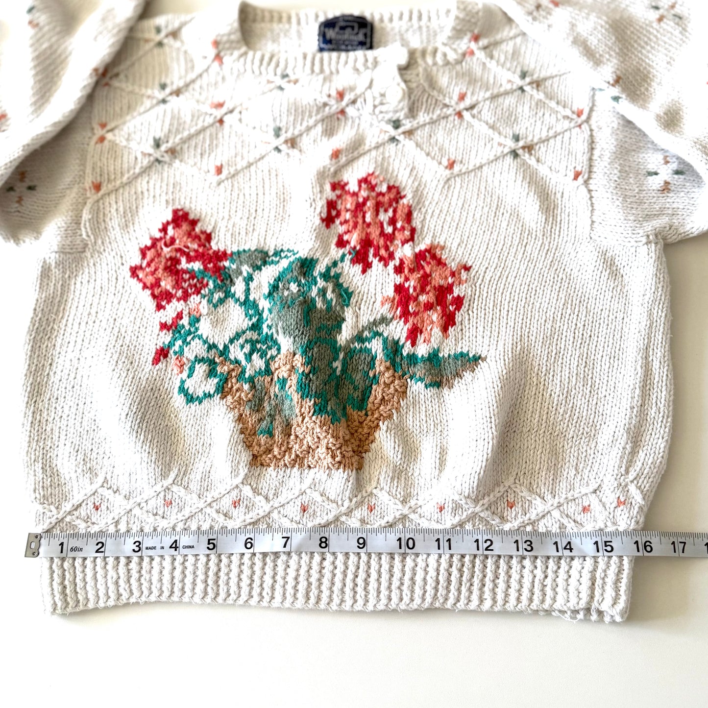 Knitted sweater with floral design and measurement tape for scale