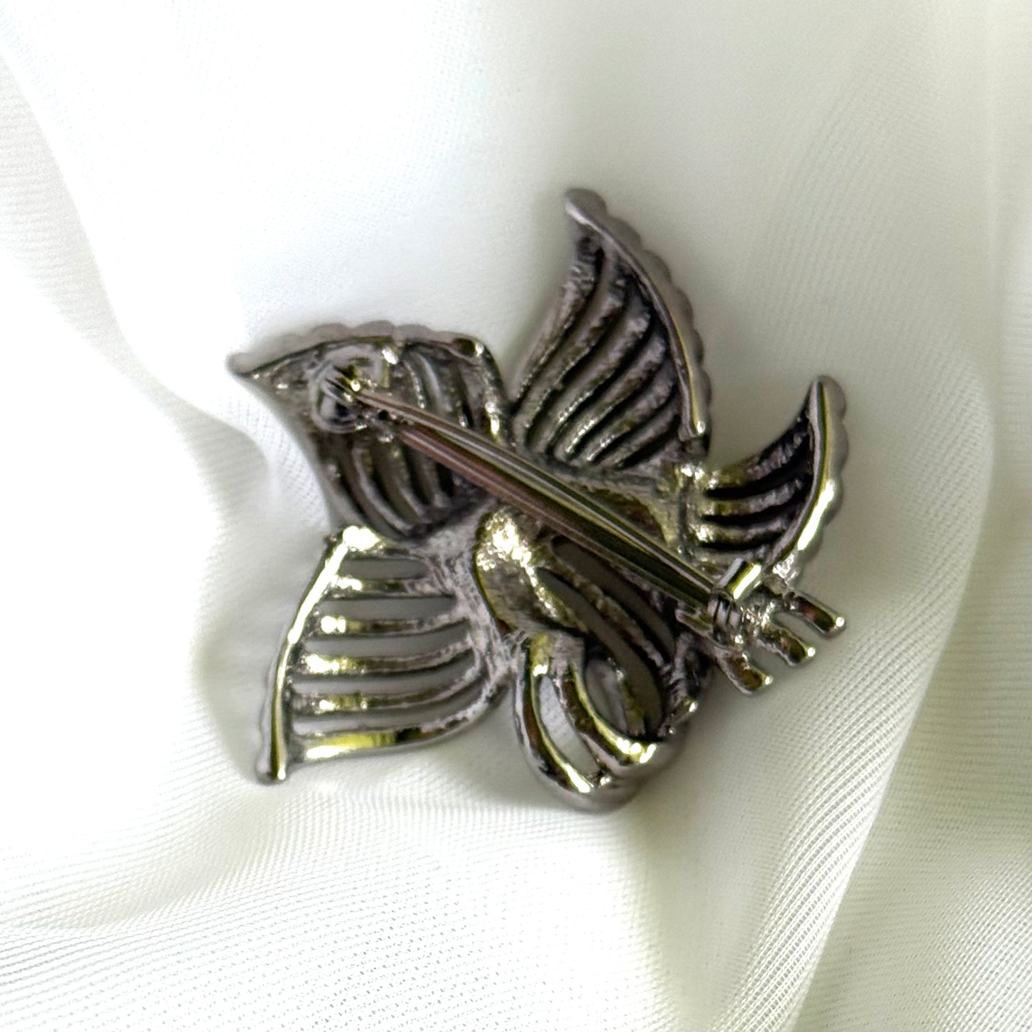 Metallic flower-shaped brooch on a white fabric background