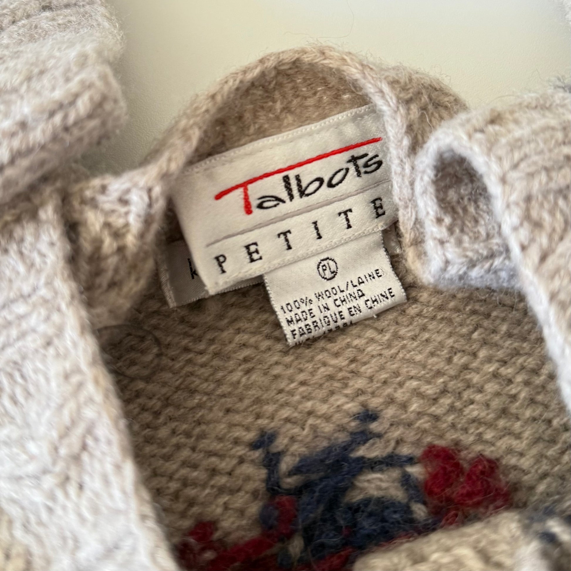 Close-up of a knitted product with a 'Talbots Petite' label on a plain background