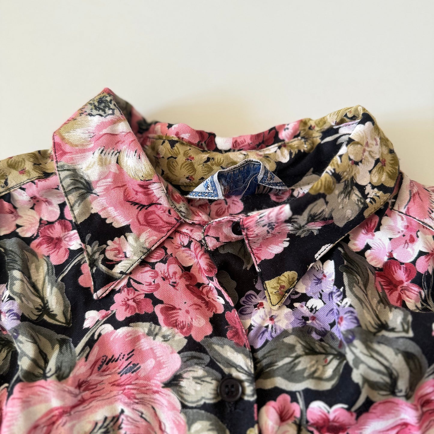 Close-up of a floral shirt collar with pink and green flowers on a plain background