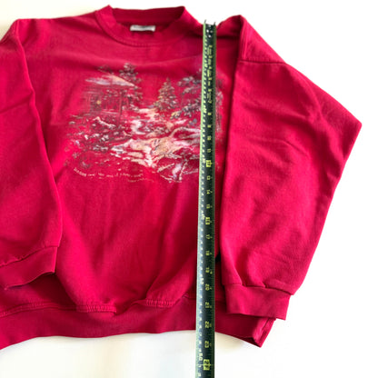 Bold pink sweatshirt / crewneck with a winter scene on the front  laid on a white backdrop - with a measuring tape laid out on it. 