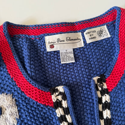 Close-up of a blue and red knitted garment with labels indicating hand-knitted quality.