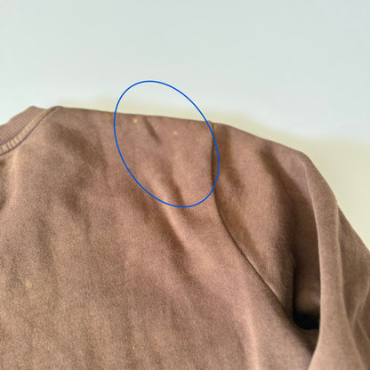 Brown sweater with a blue circle highlighting a spot on the fabric.