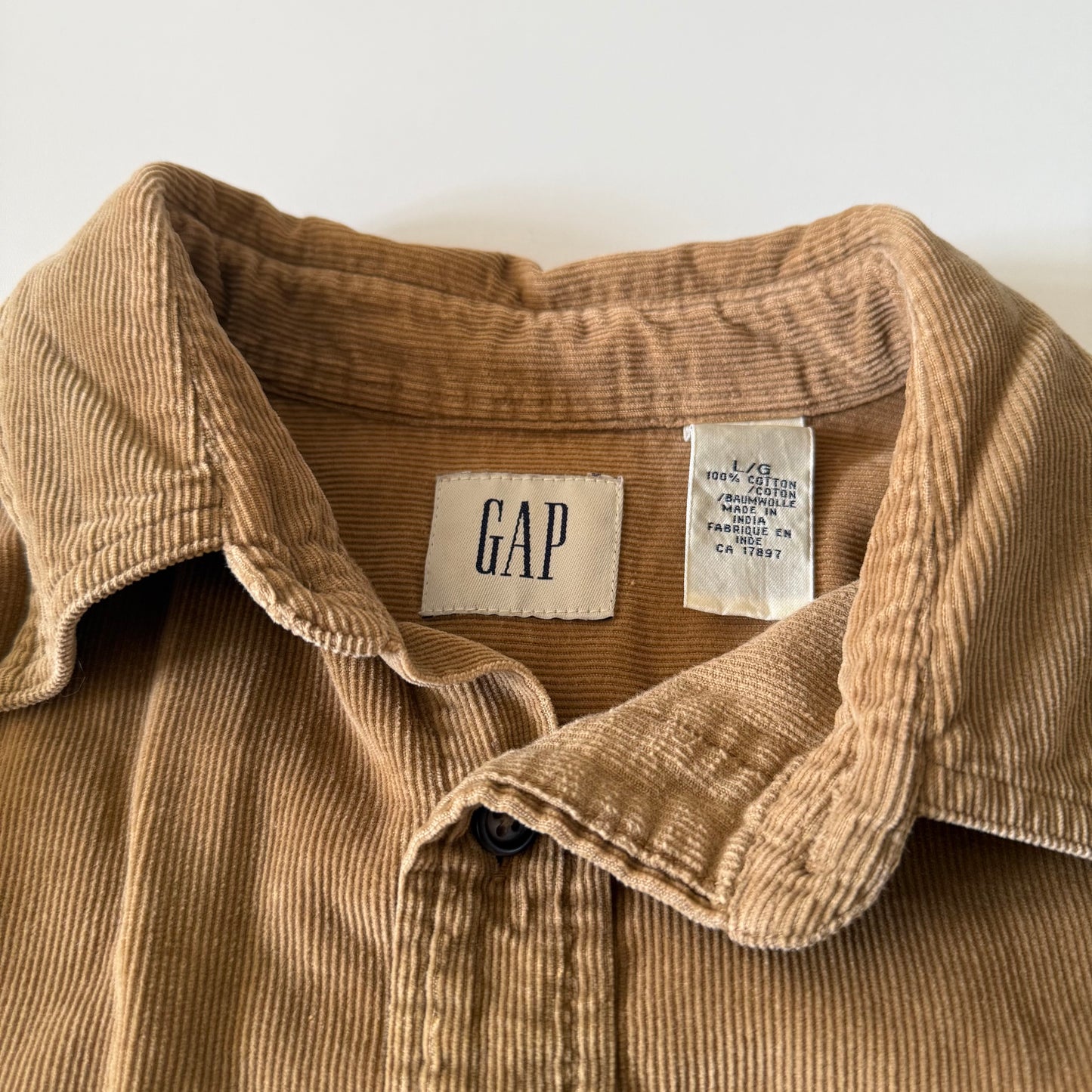 Close-up of a brown corduroy shirt with a GAP label on a white background