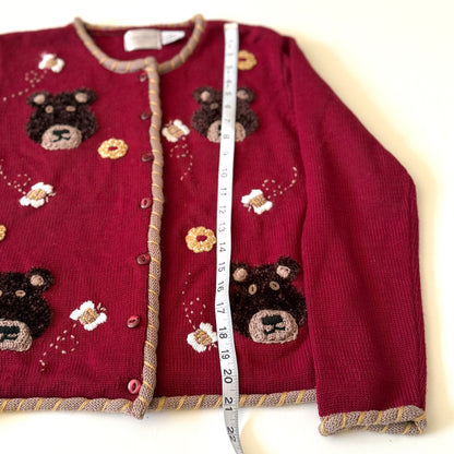 Red sweater with bear designs and a measuring tape for size reference on a white background