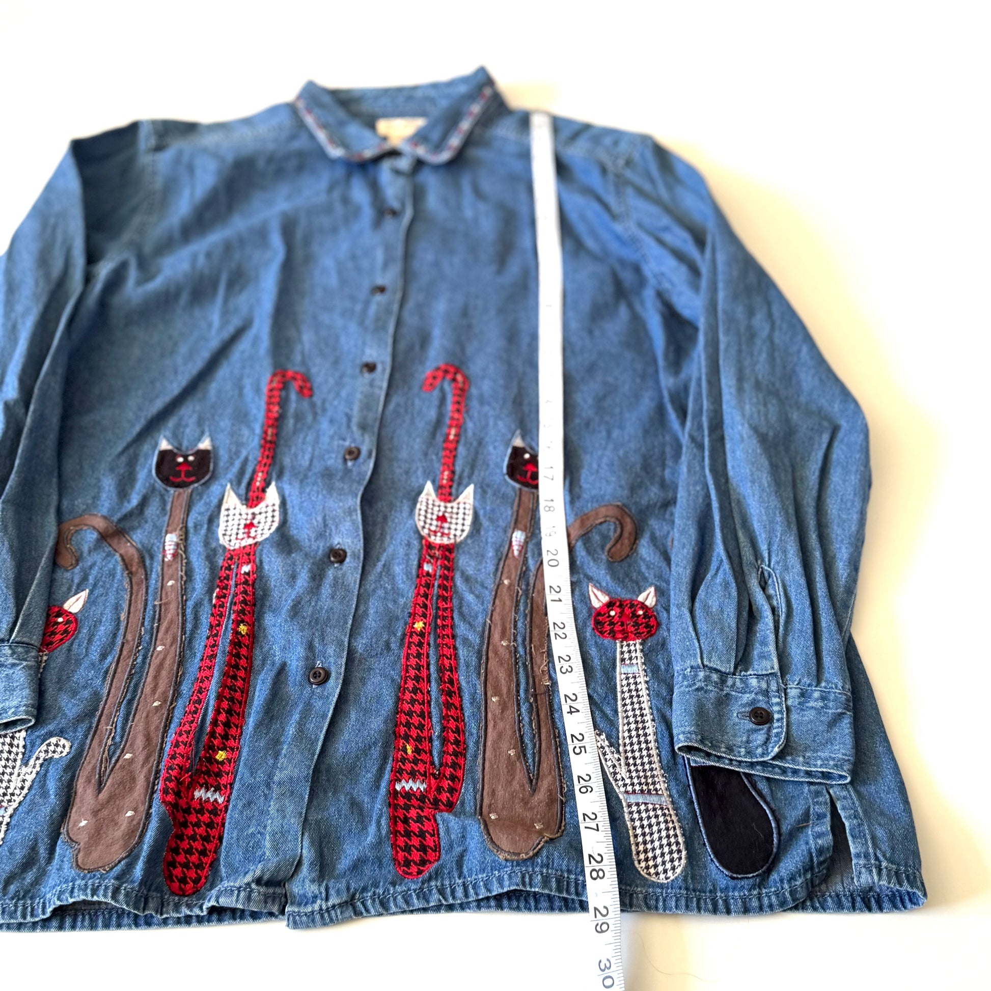 Denim shirt with cat appliqués on a white background
