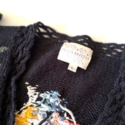 Black embroidered sweater with a brand tag on a white background