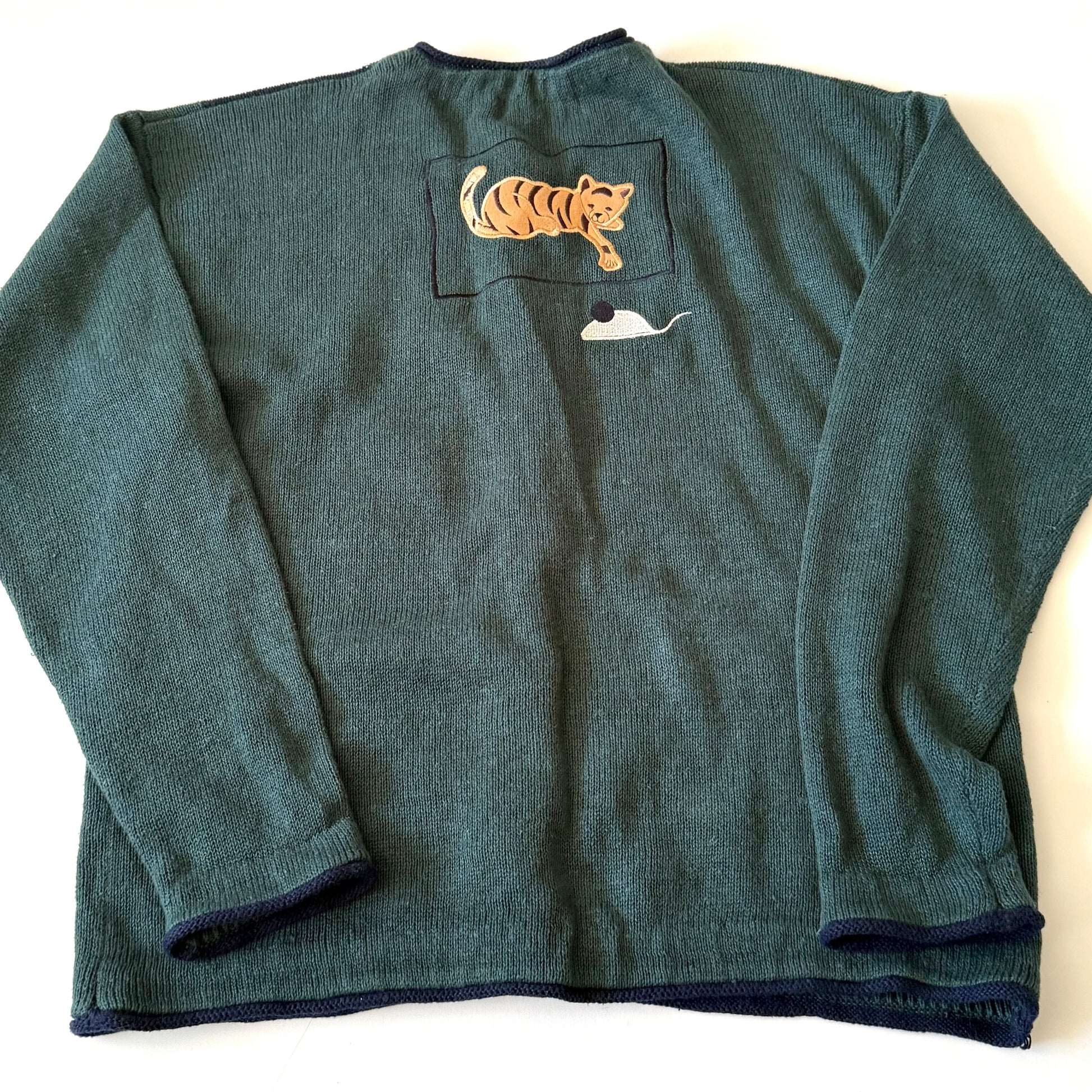 Green sweater with a pocket featuring a tiger and whale design on a white background