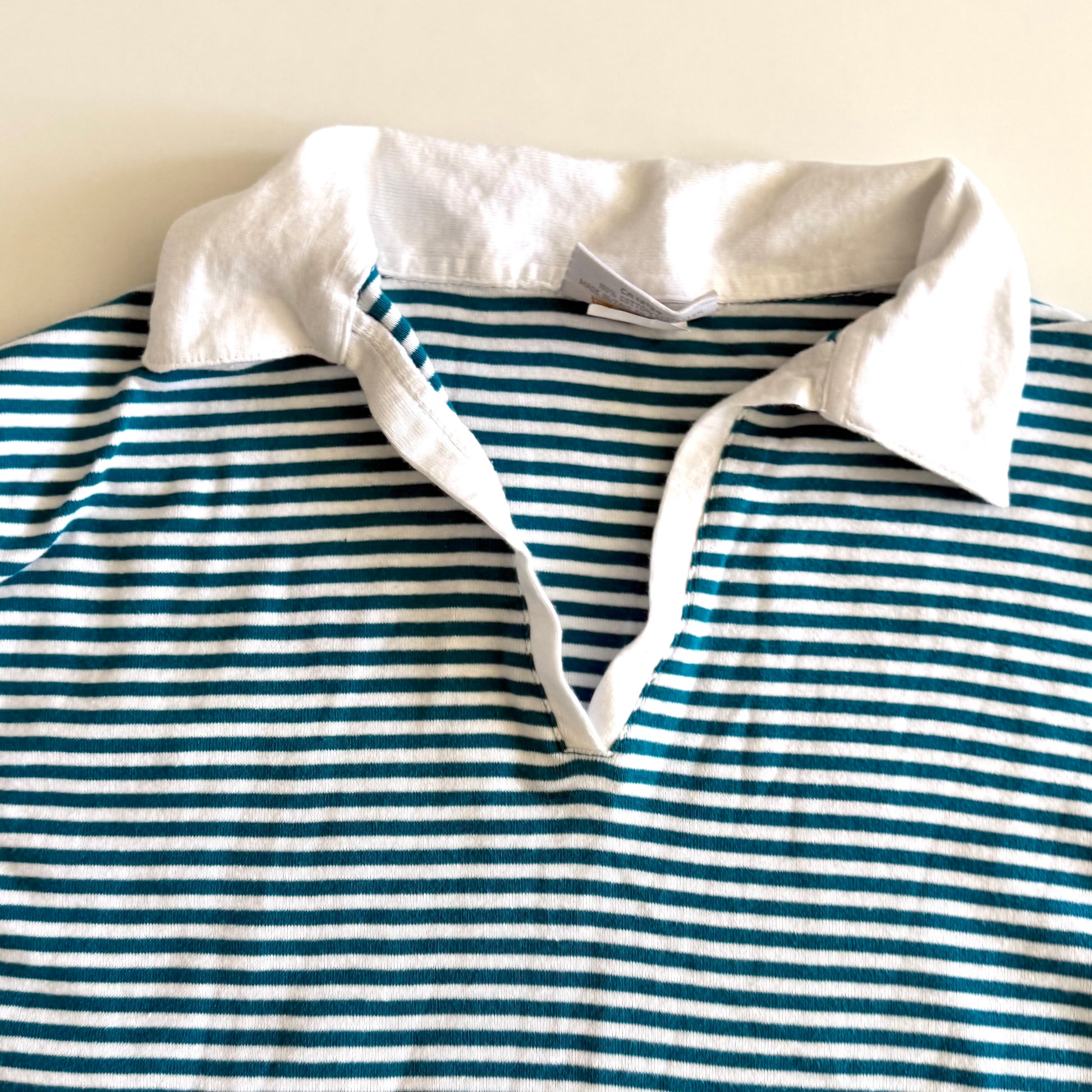 White and turquoise striped tank top with polo neckline, on a white backdrop. 