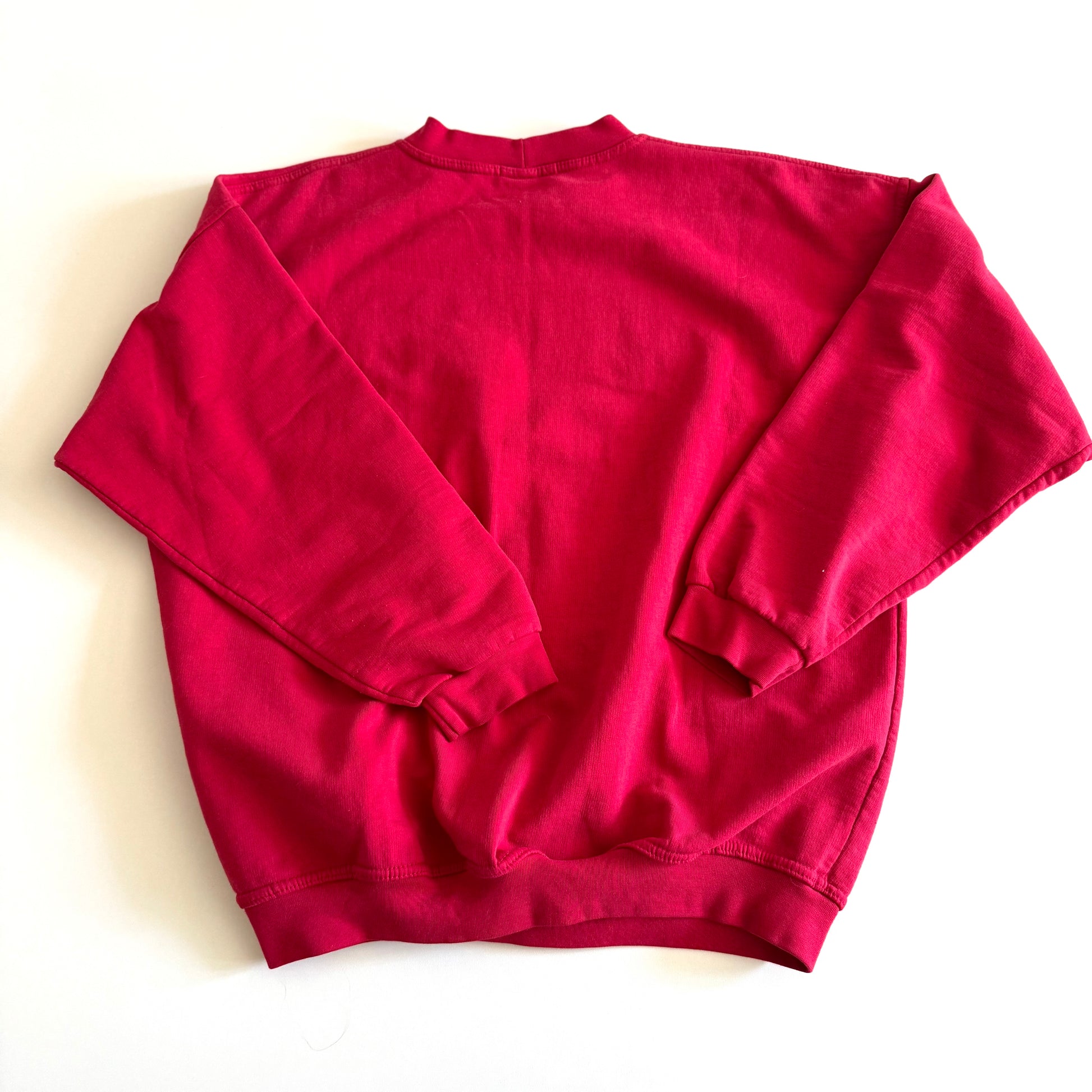 Backside of Bold pink sweatshirt / crewneck with a winter scene on the front  laid on a white backdrop. 