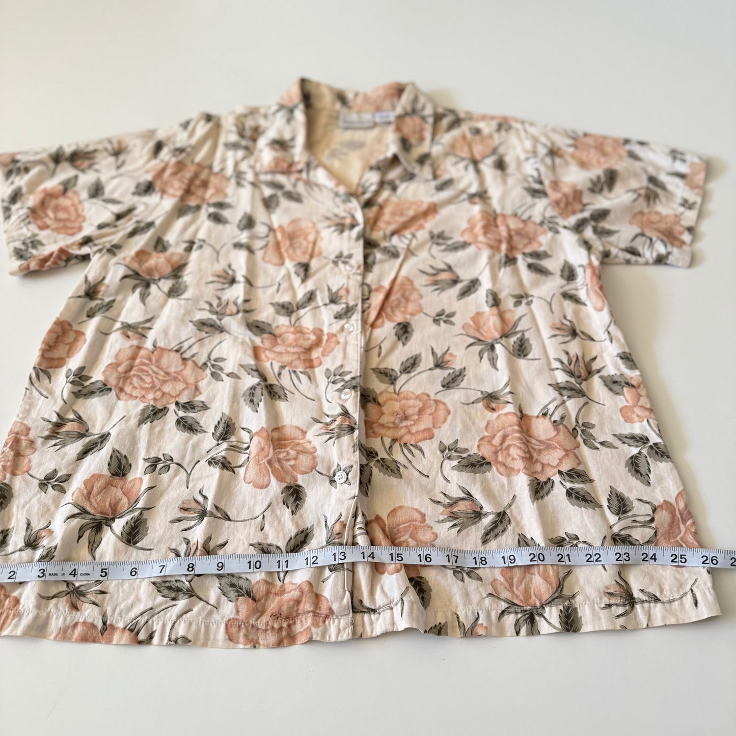 Floral-patterned garment with a measuring tape for size reference on a white background