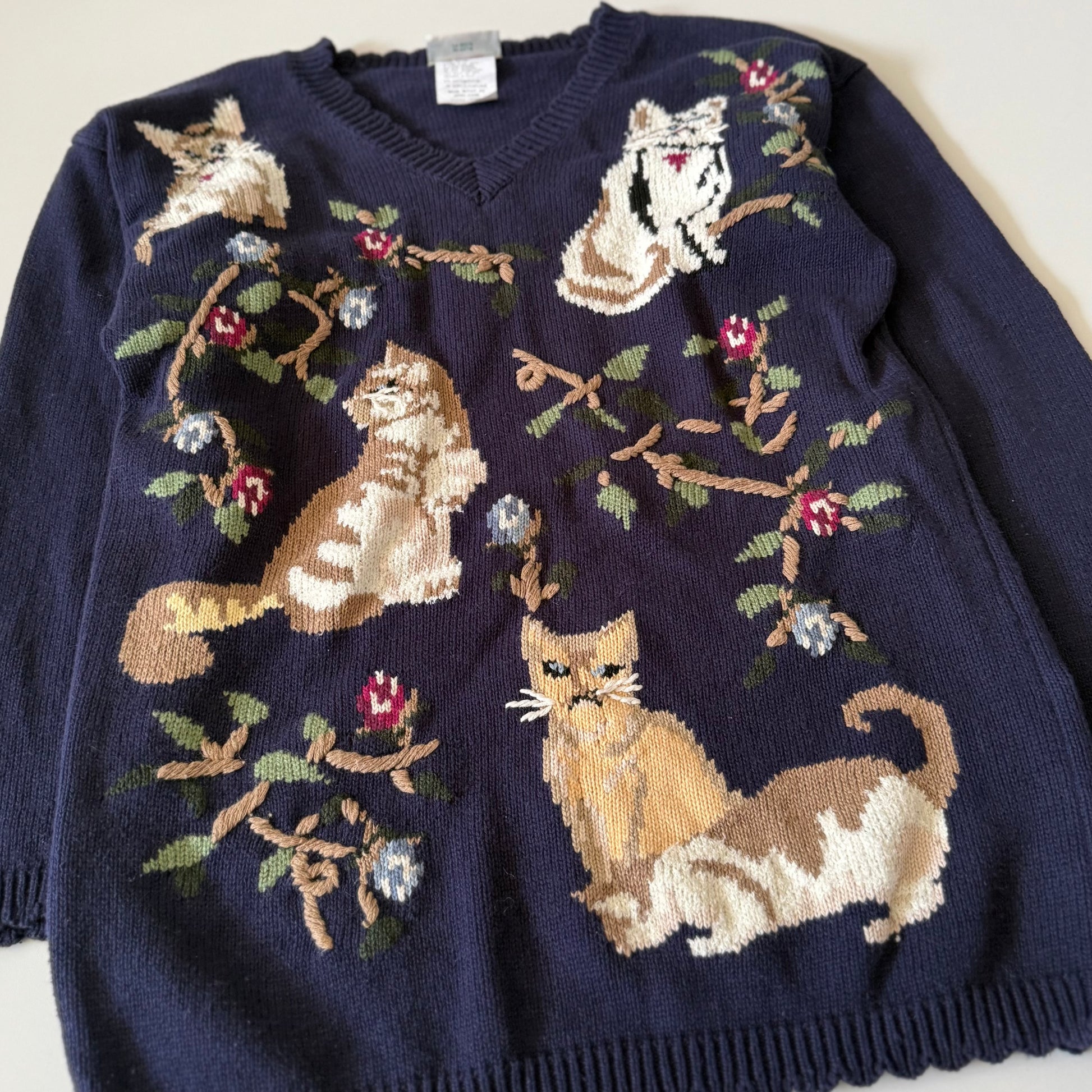 Navy blue sweater with cat and floral pattern on a white background