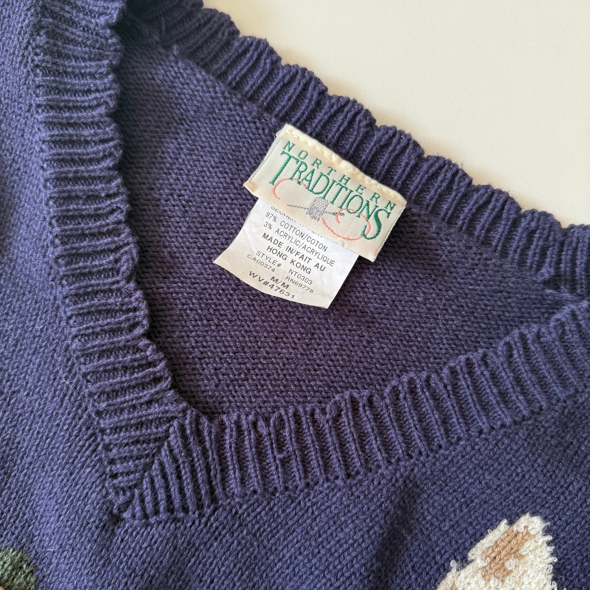 Close-up of a blue knitted sweater with a tag on a light background
