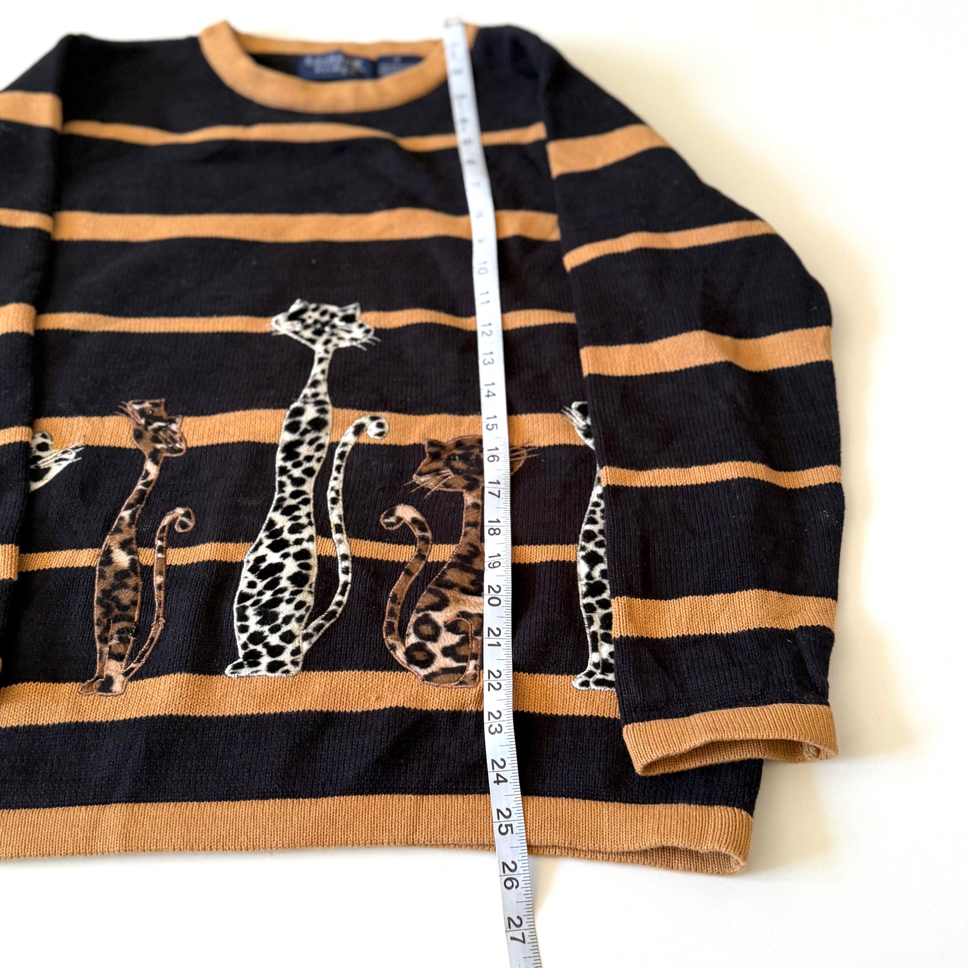 Black and brown striped sweater with animal prints, measured against a tape measure.
