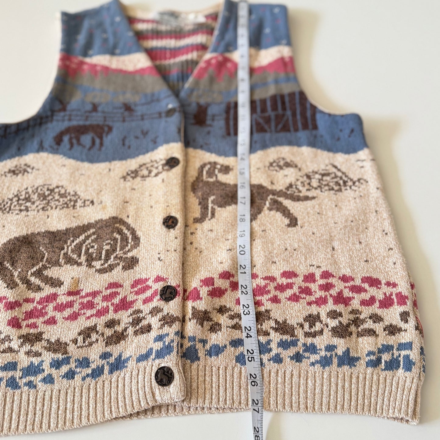 Knitted vest with animal pattern and measuring tape on a white background