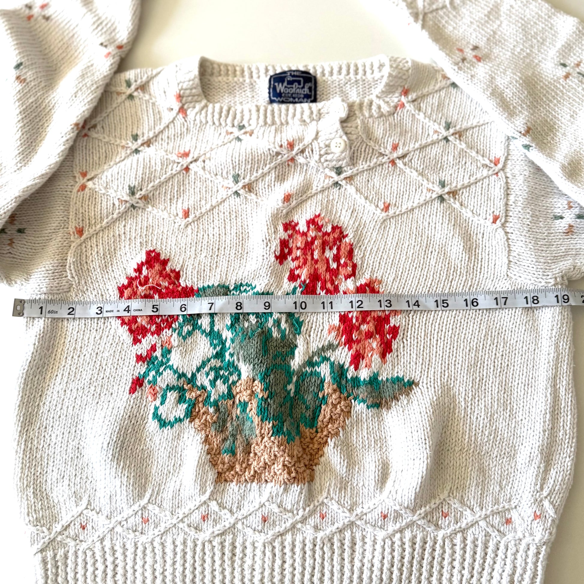 Knitted sweater with floral design and measuring tape for size reference