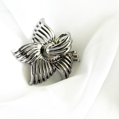 Silver flower-shaped brooch on a white fabric background