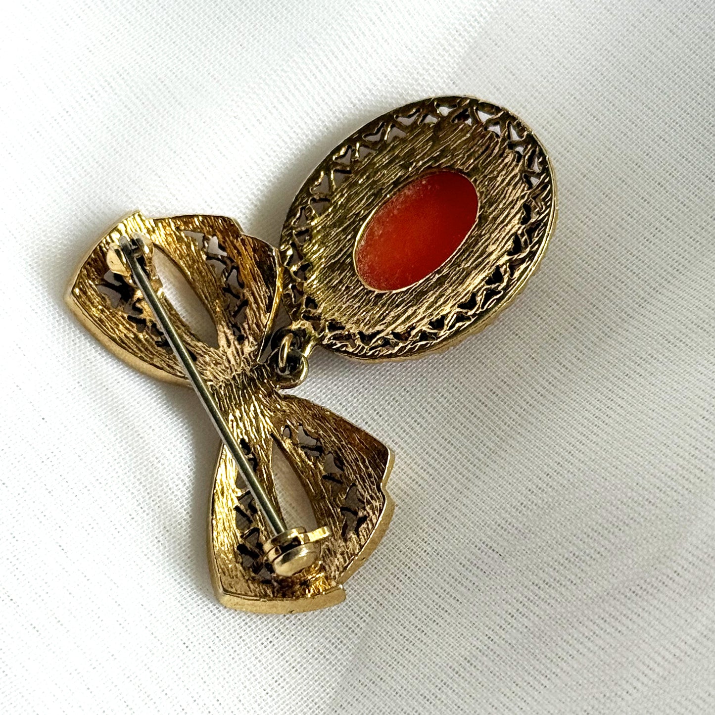 Gold brooch with a red stone on a white background