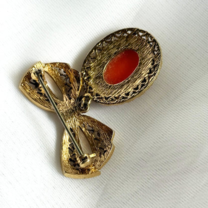 Gold brooch with a red stone on a white background