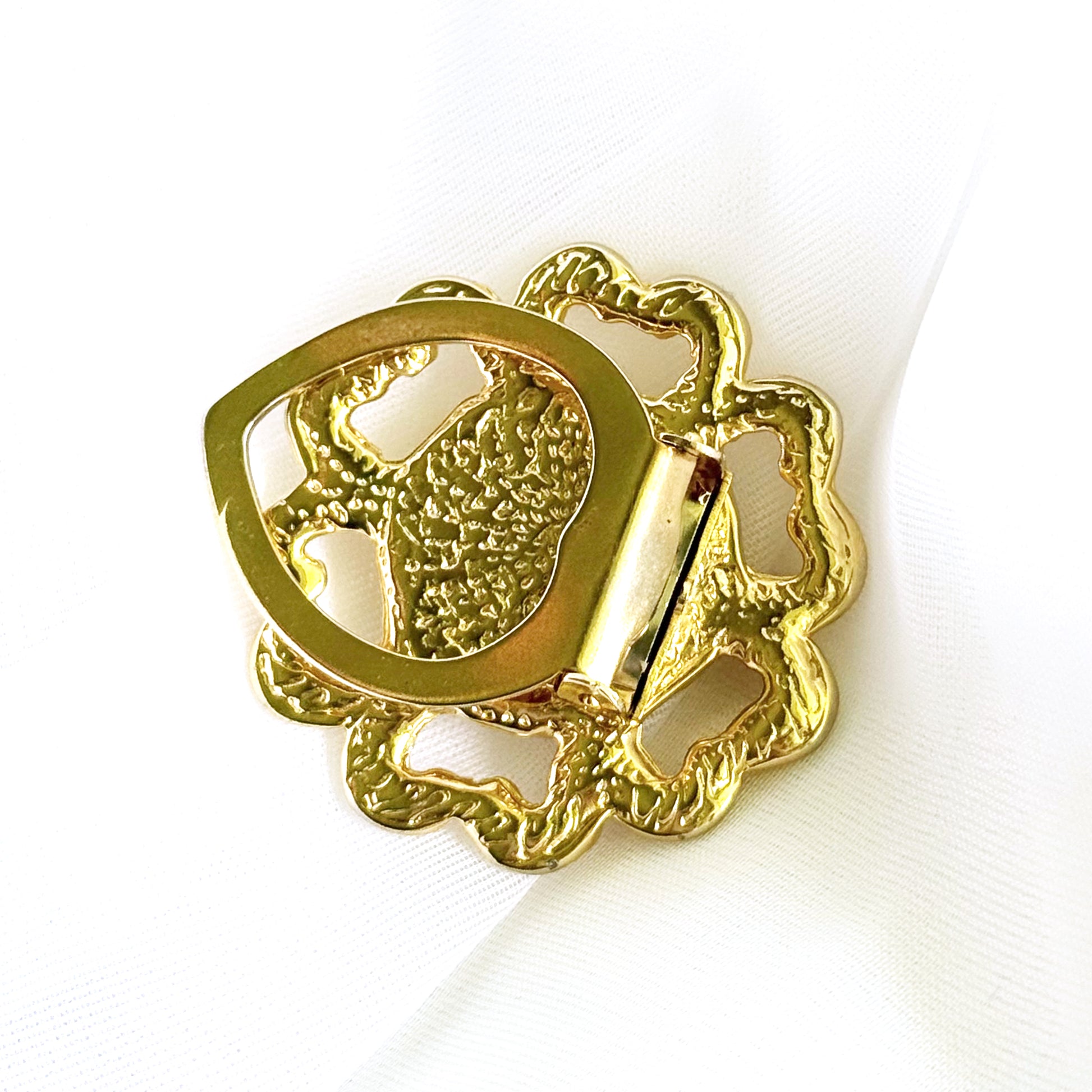 Gold belt buckle with intricate design on a white background