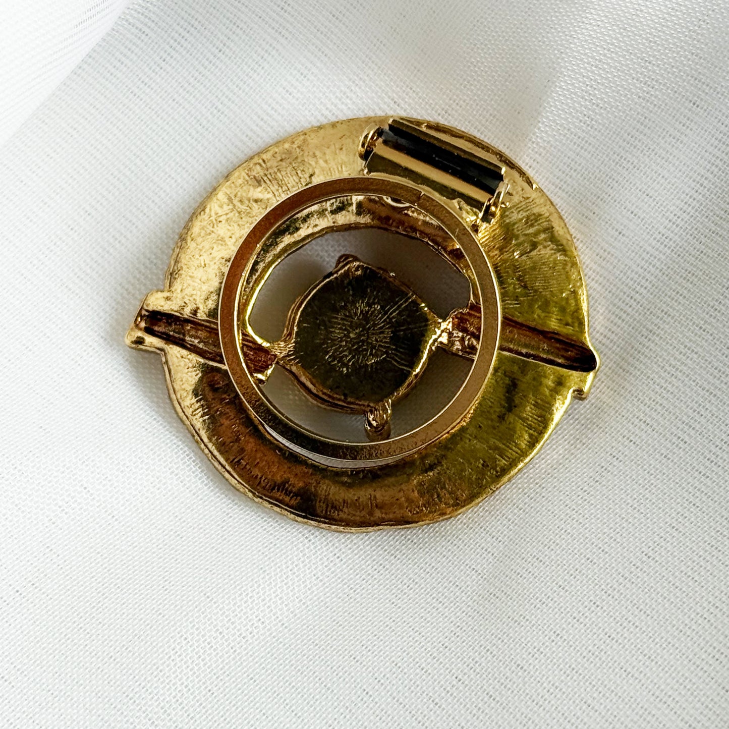Gold brooch on a white fabric background