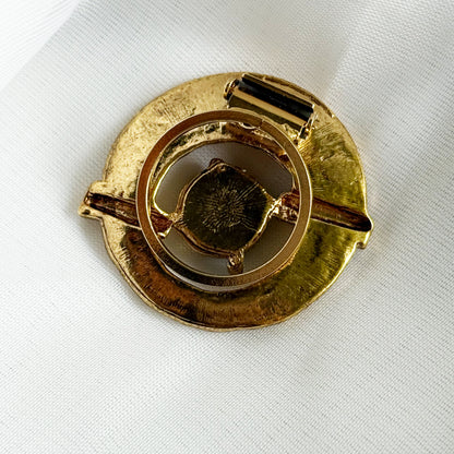 Gold brooch on a white fabric background