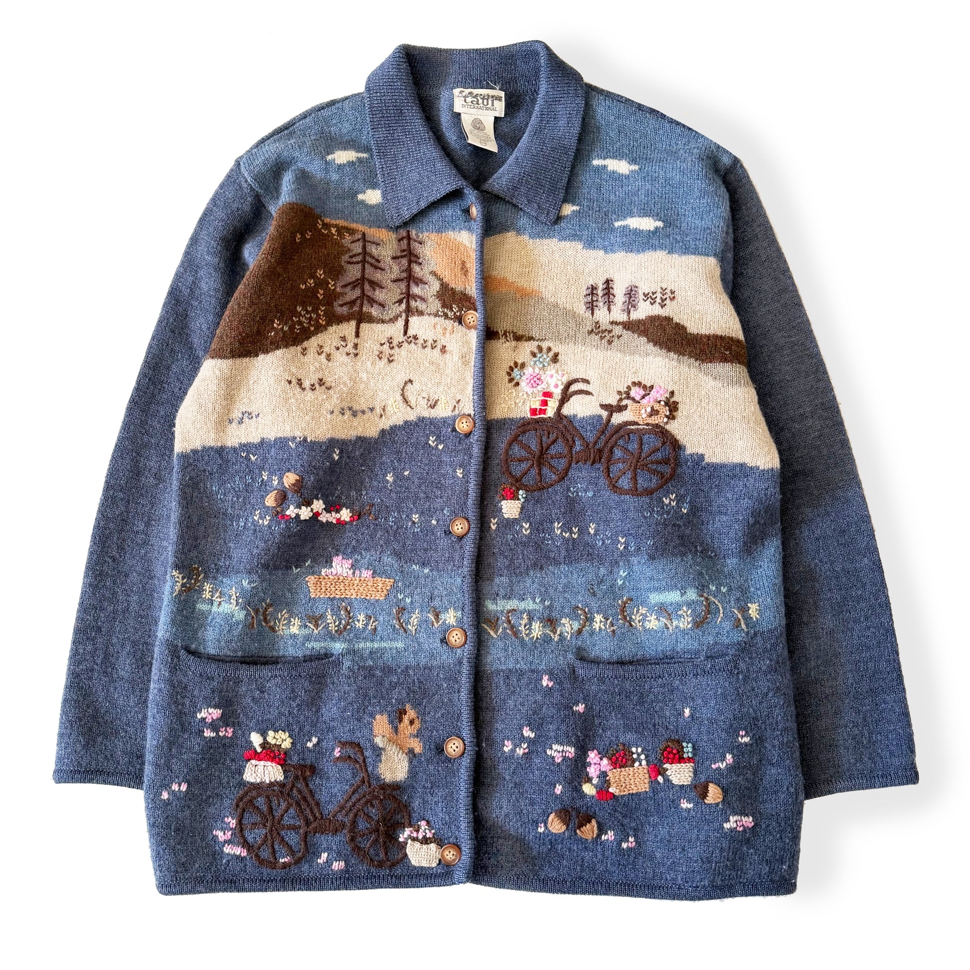 Blue jacket with embroidered scenes of a bicycle and nature on a white background