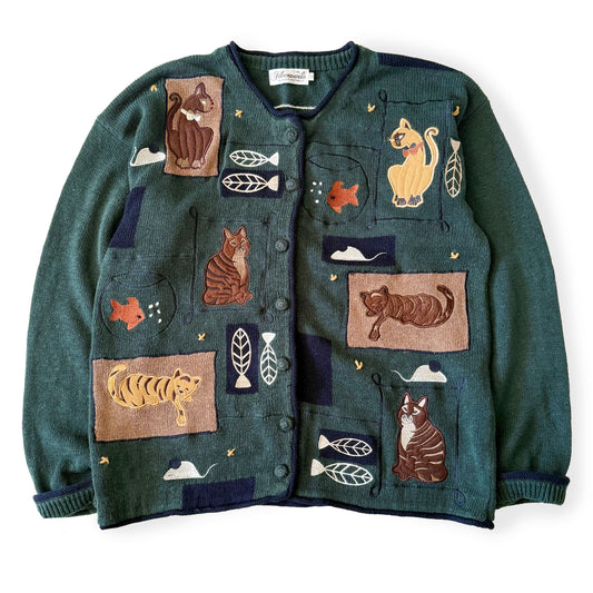 Green sweater with animal-themed patches on a white background