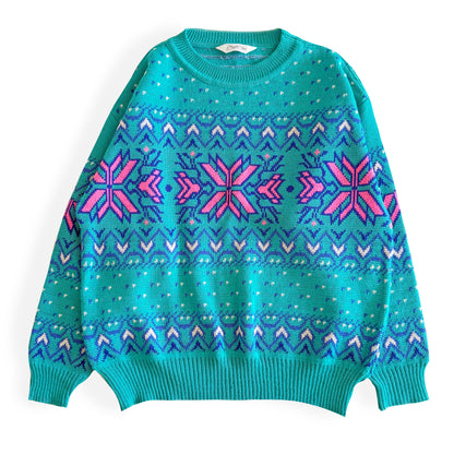 Teal and pink sweater with an aztec / snowflake adjacent style pattern, on a white background. 