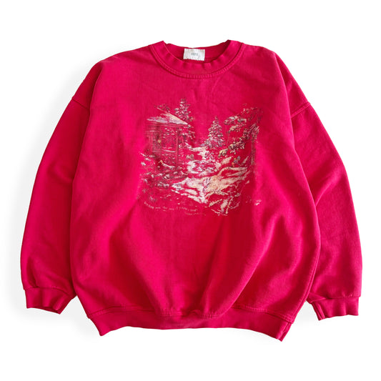 Bold pink sweatshirt / crewneck with a winter scene on the front  laid on a white backdrop. 