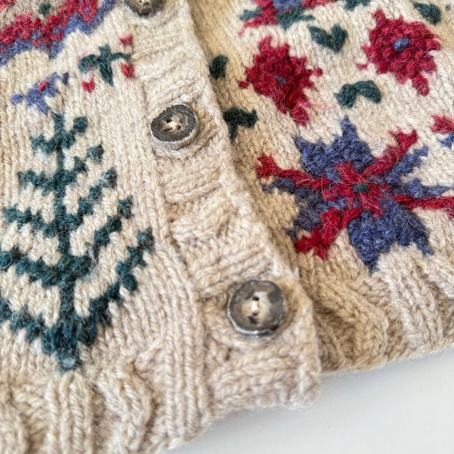 Close-up of a knitted sweater with floral and snowflake patterns.