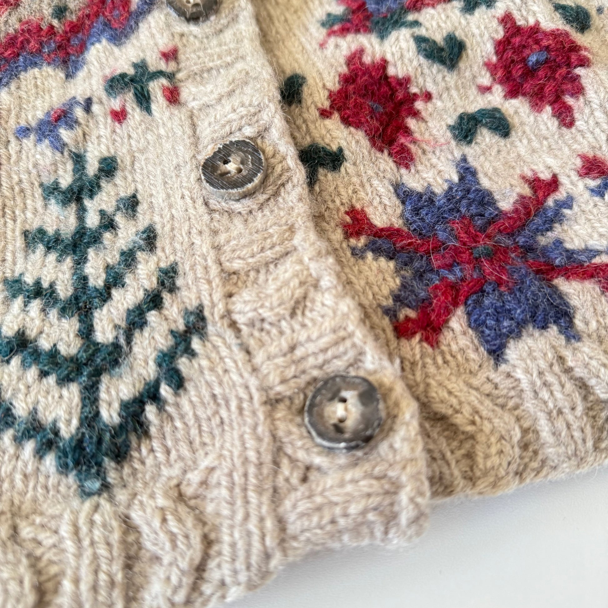 Close-up of a knitted sweater with floral and snowflake patterns.