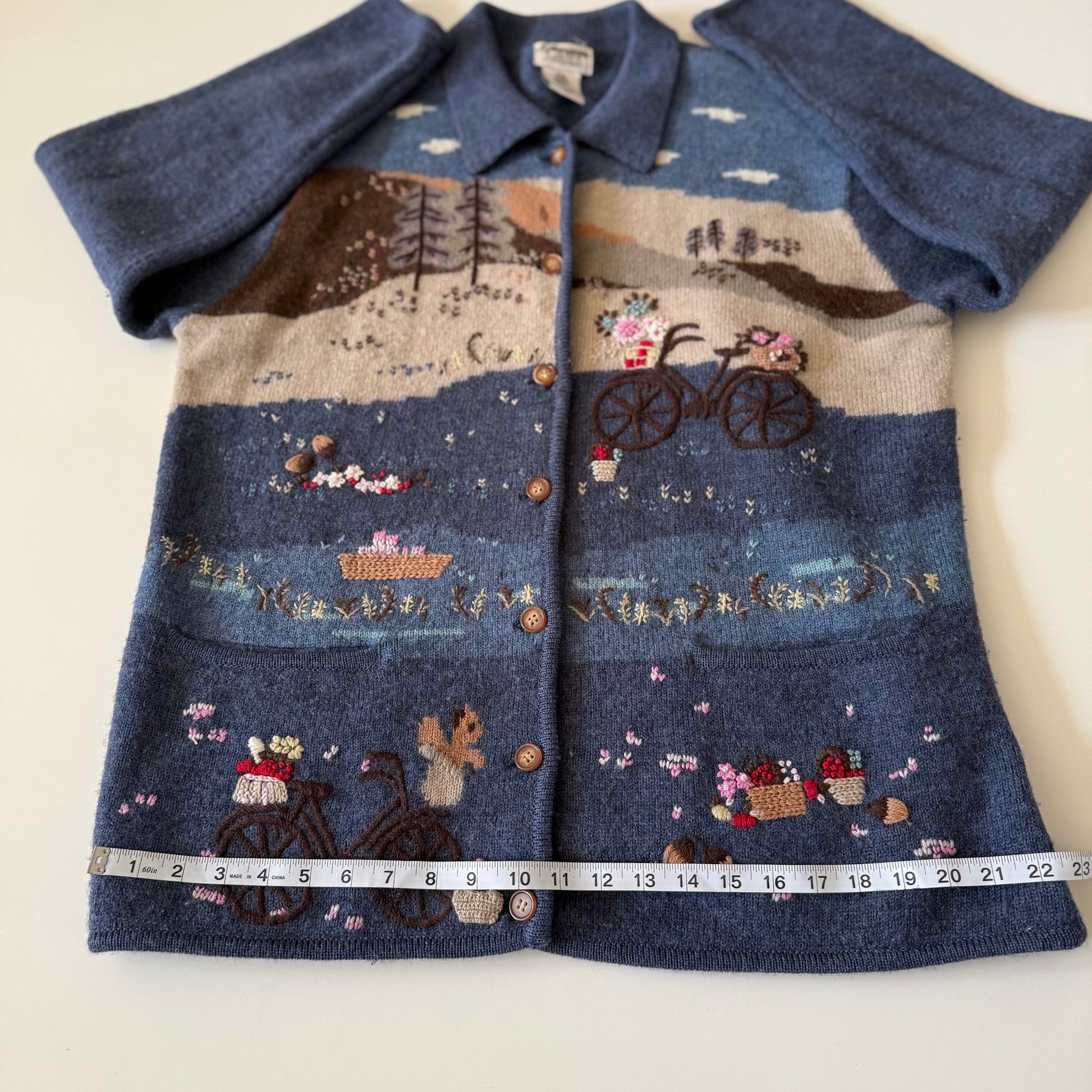 Blue embroidered jacket with a scenic design on a white background