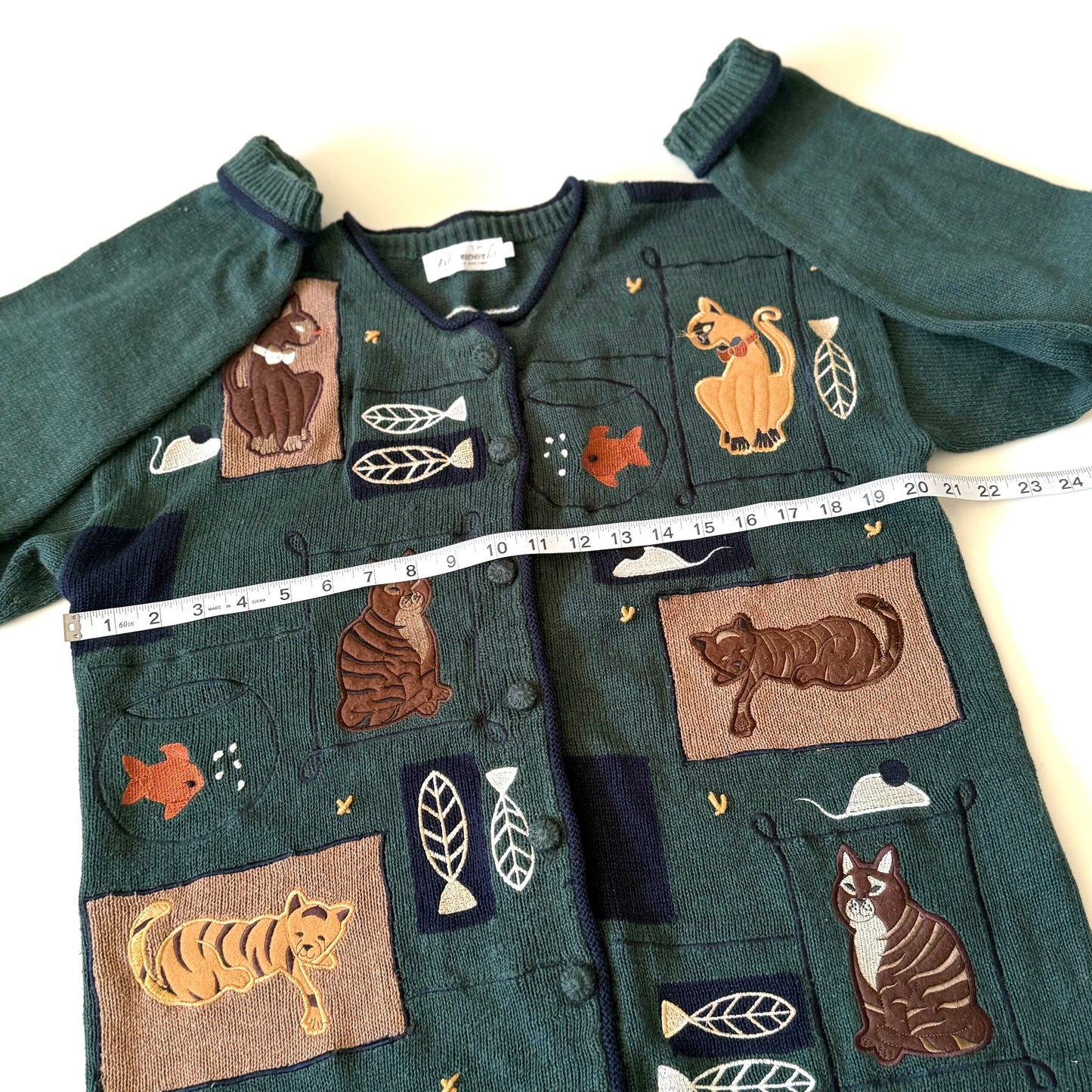 Green sweater with animal appliqués on a white background