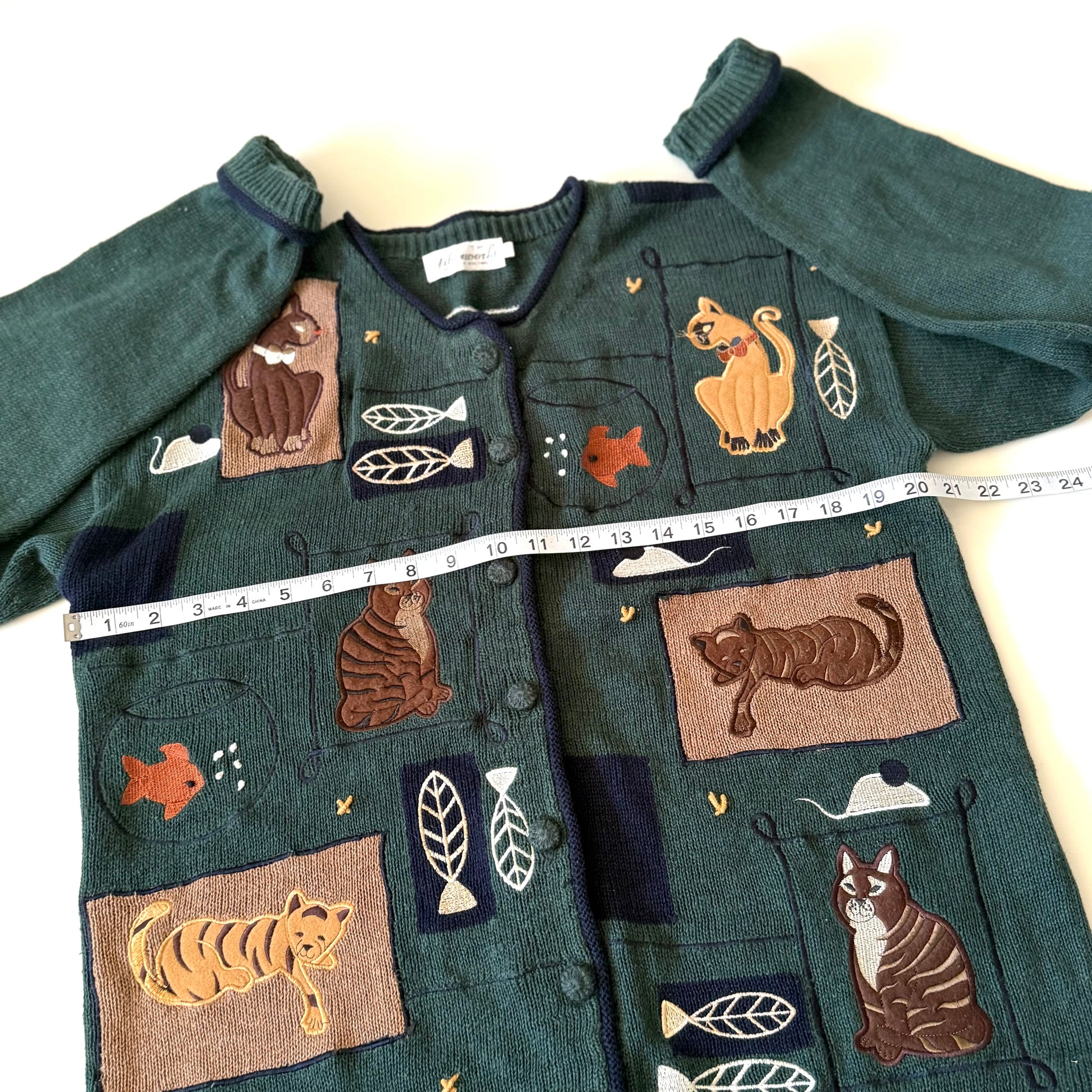 Green sweater with animal appliqués on a white background