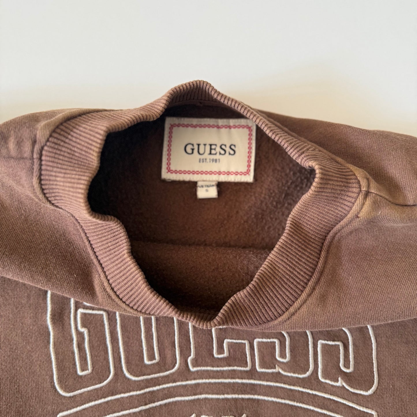 Brown sweater with Guess logo on a white background