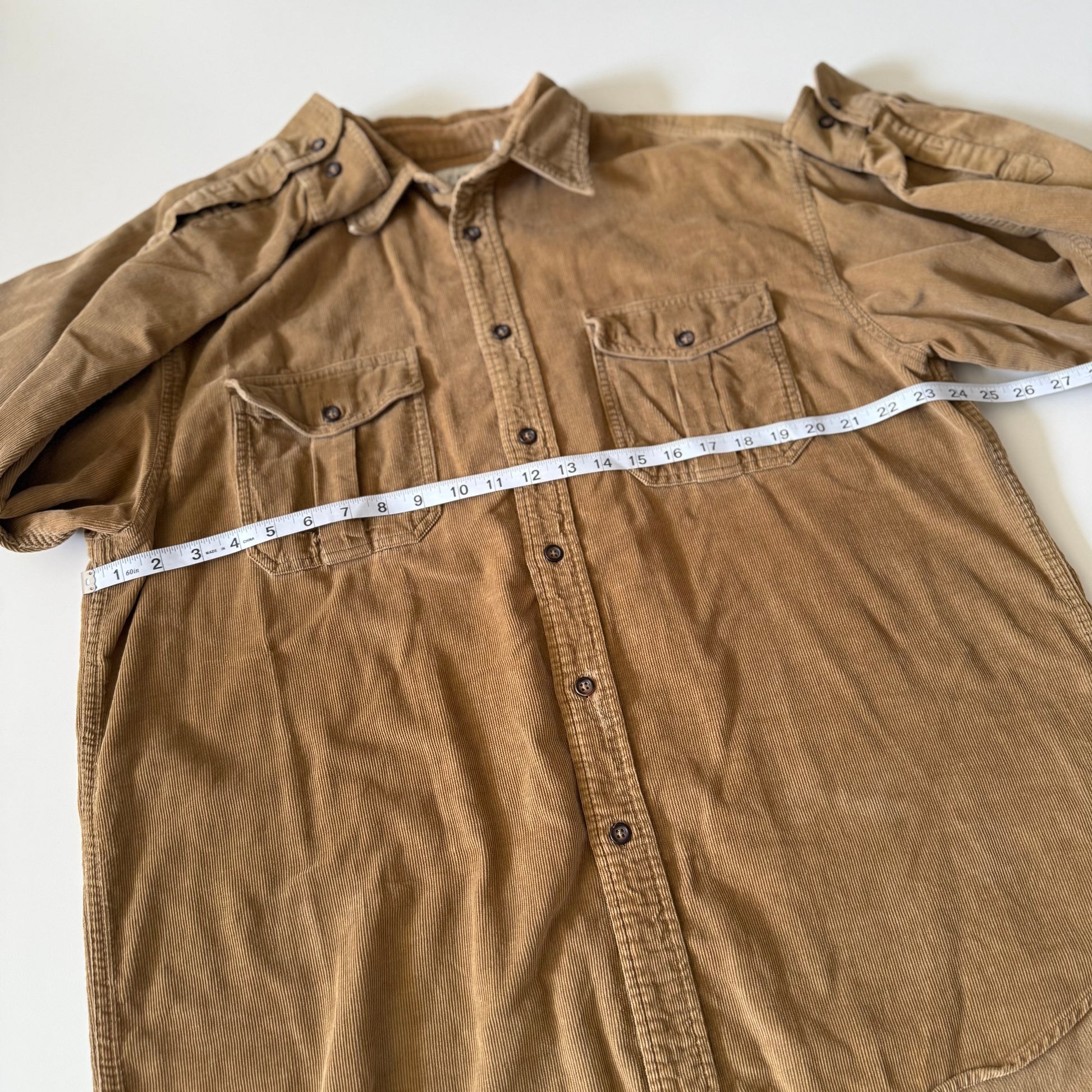 Brown shirt with a measuring tape laid across it on a white background