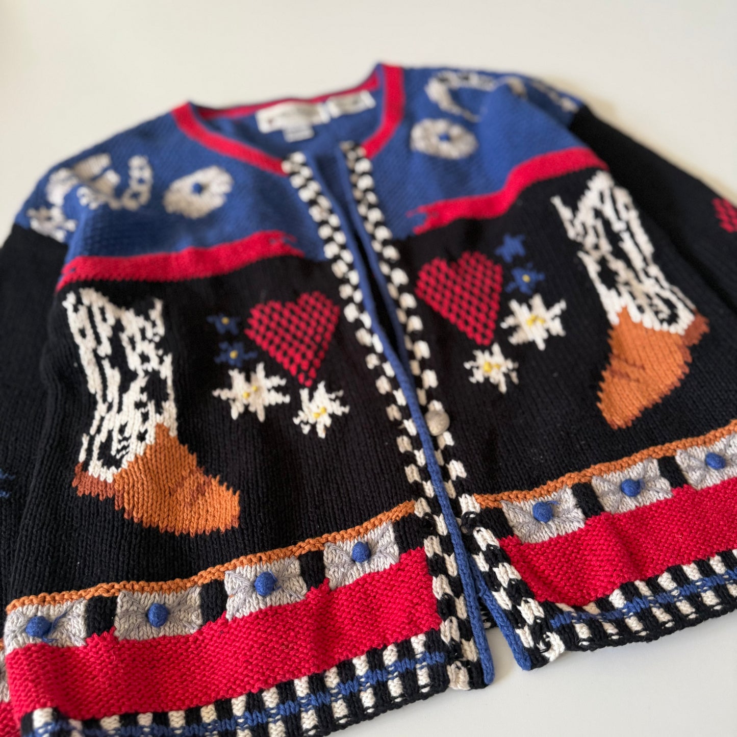 Colorful knitted cardigan with patterned design on a white background