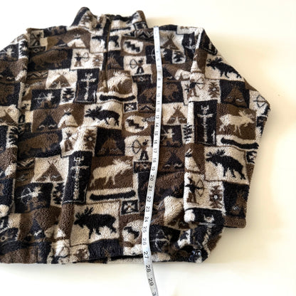 Moose and other camping motif quarter zip fleece on a white background with a measuring tape on it. 