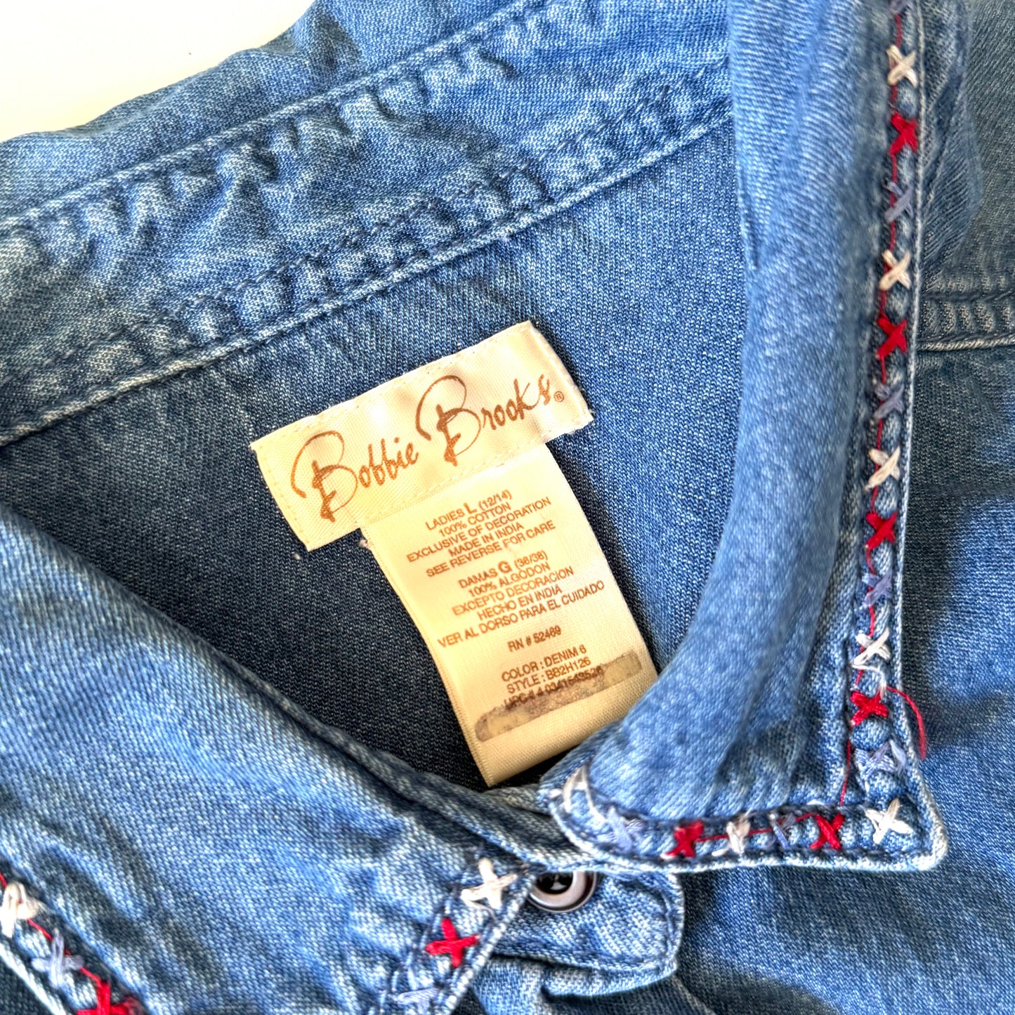 Close-up of a blue denim jacket with a label inside, featuring the brand 'Bobbie Brooks'.