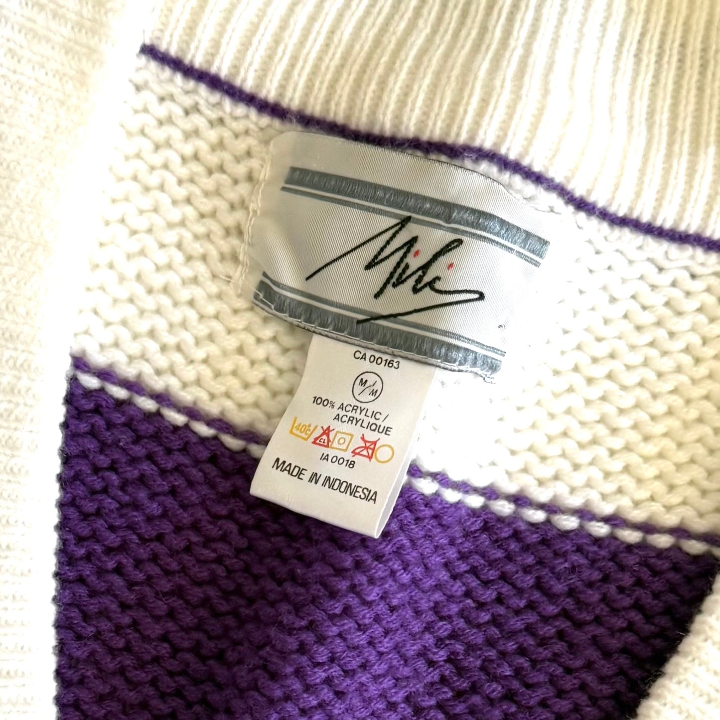 Close up of a clothing product tag that reads: MILI(brand), Size M, 100% Acrylic, MADE IN INDONESIA. 