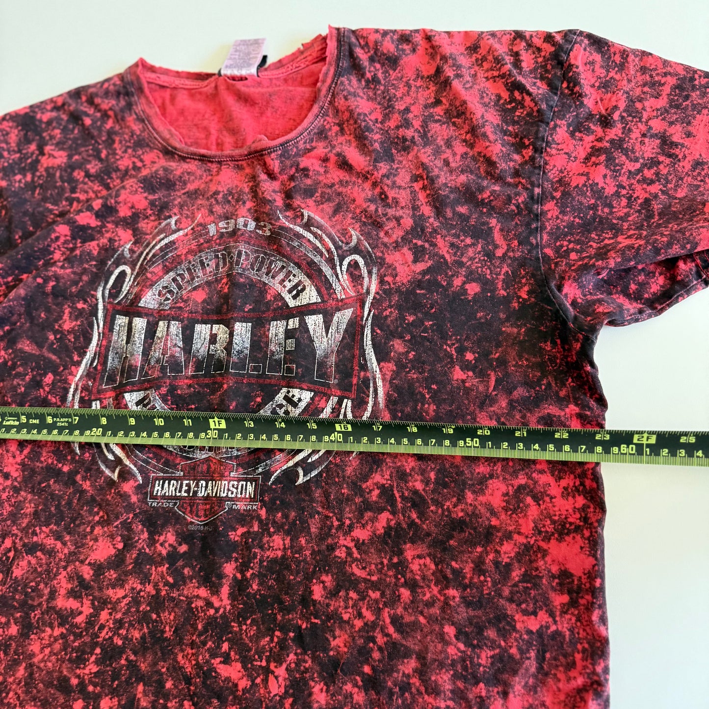 Pinky red t-shirt with black ie dye effect, and the harley davidson logo on the front - on a white background.  With a tape measure aid on it. 