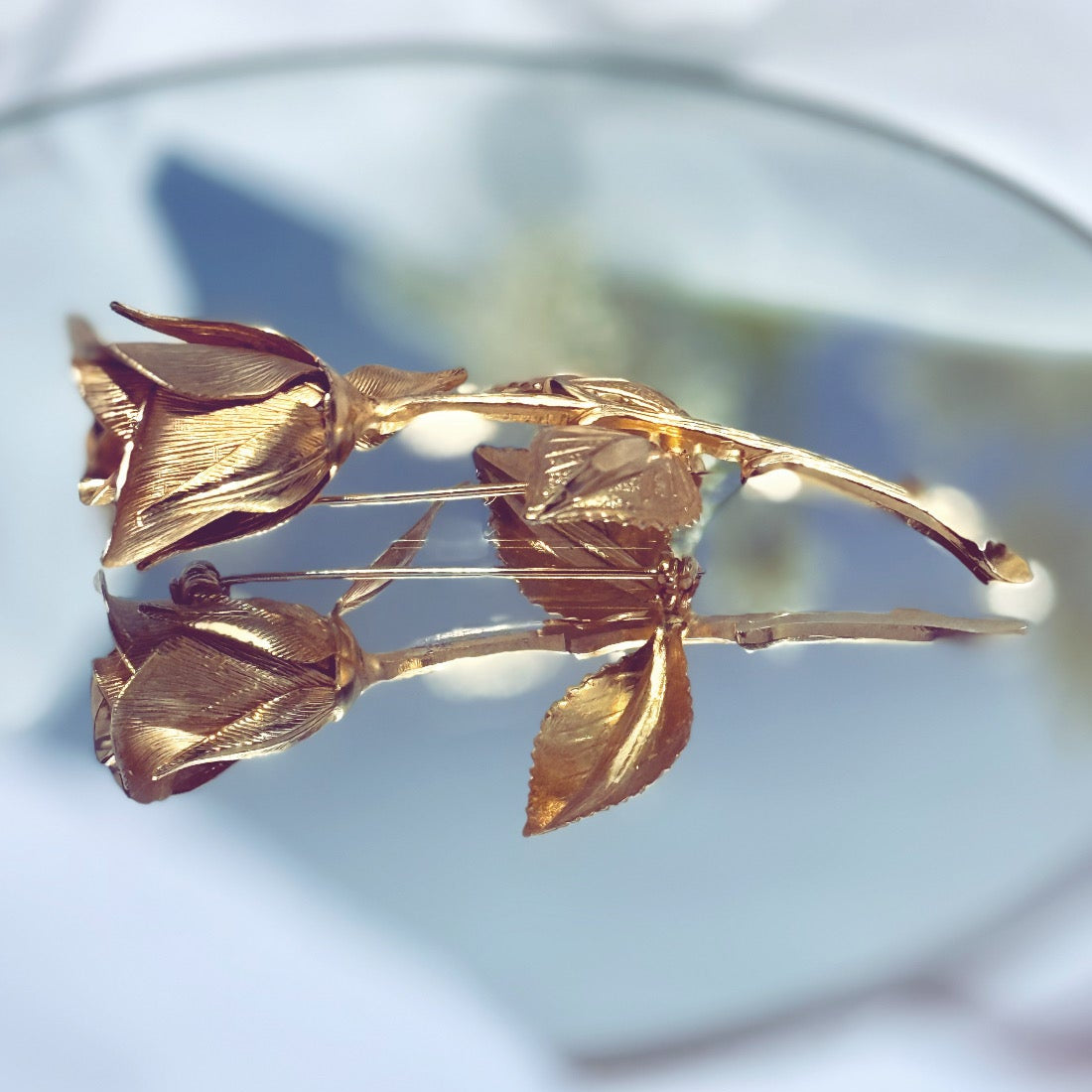 Gold rose-shaped brooch on a light blue background