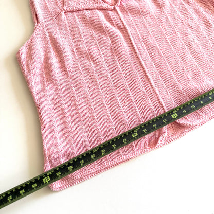 Light pink knit style tank top, with folded out collar opening on a white backdrop - with a measuring tape laid on top. 