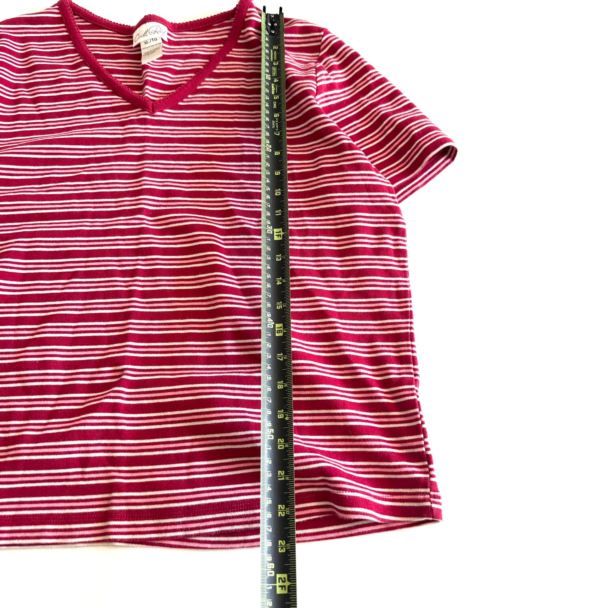 White, pink, and red striped t-shirt with a v-neck collar on a white backdrop - plus a measuring tape laid out on it. 