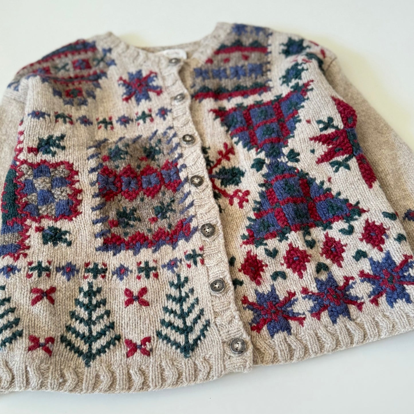 Knitted cardigan with colorful geometric pattern on a white background
