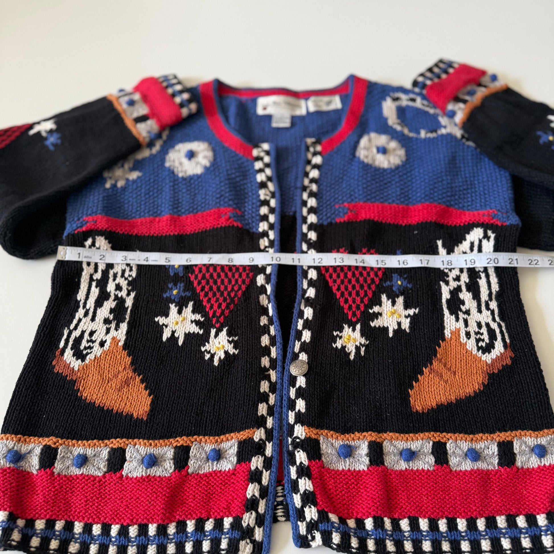 Knitted sweater with colorful patterns and a measuring tape on a white background