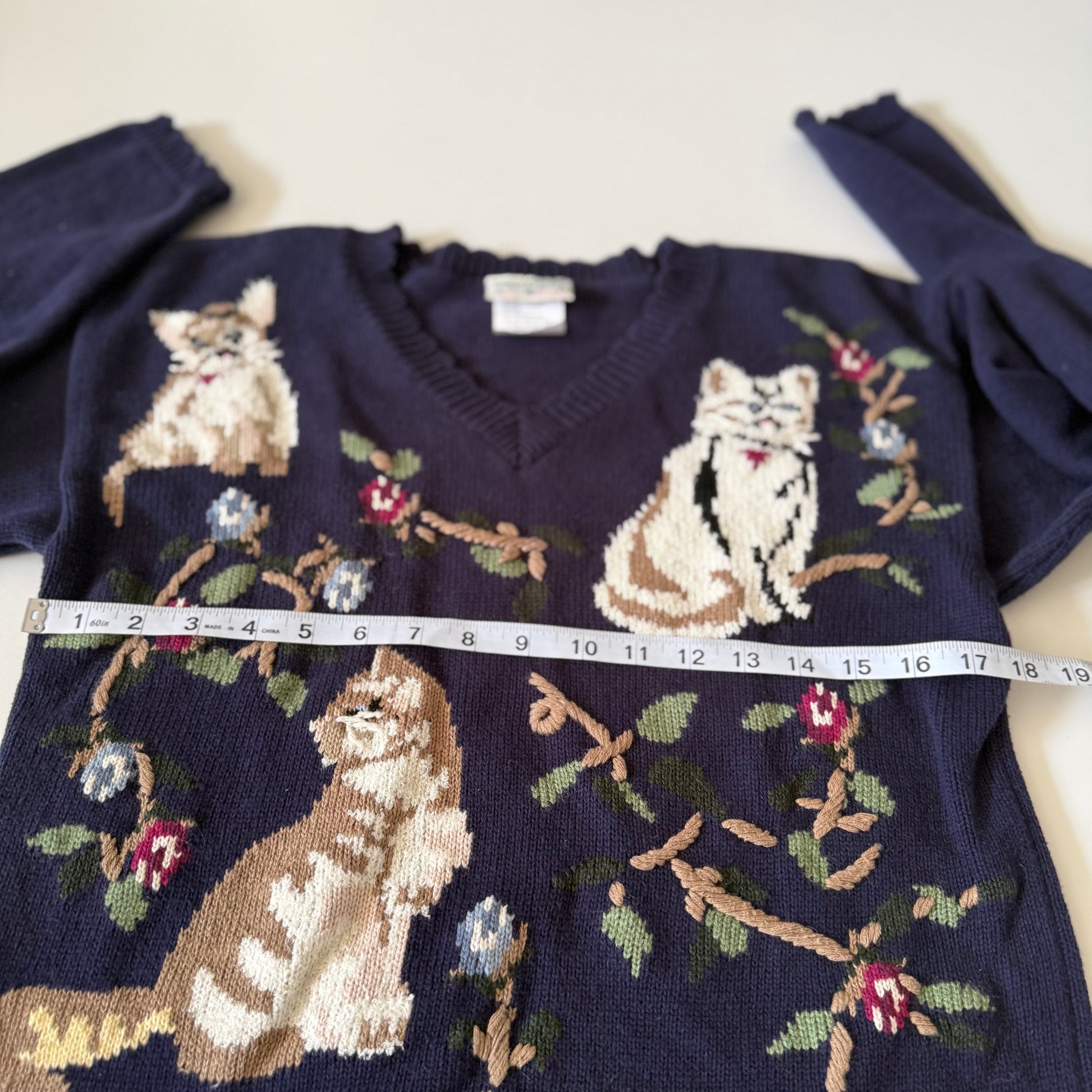 Navy blue sweater with cat and floral pattern, measured with a tape measure.