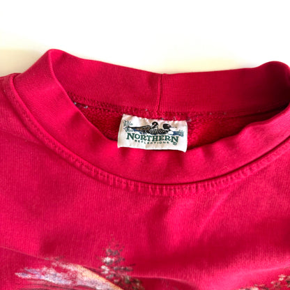 Bold pink sweatshirt / crewneck with a winter scene on the front  laid on a white backdrop with the Northern Reflection tag in focus. 