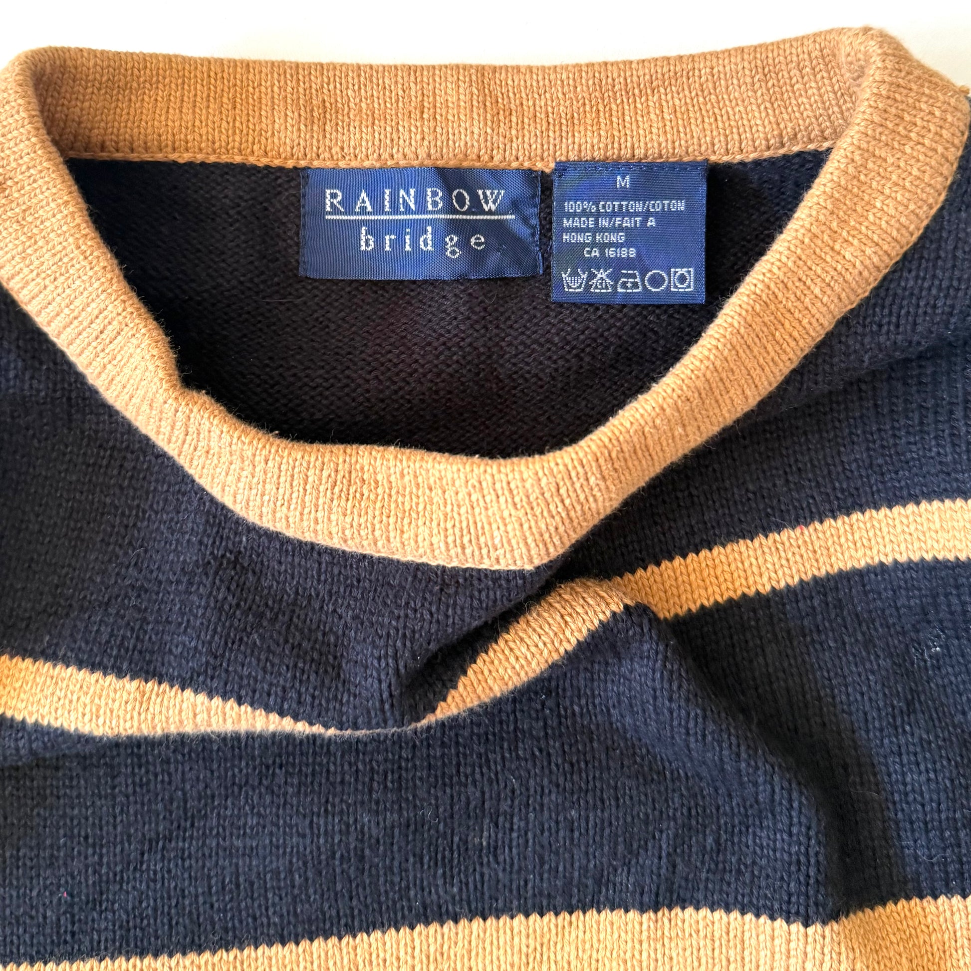 Close-up of a navy and beige striped sweater with a brand label on a white background